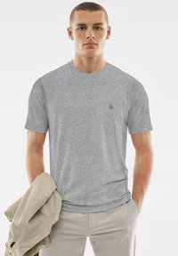 Graues T-Shirt mit Rundhalsausschnitt aus einem strukturierten Stoff, mit kurzen Ärmeln und einem dezenten Logo auf der linken Brust.