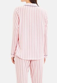 Randig pyjamasuppsättning i rosa och vitt med långa ärmar och matchande byxor, med marinblå detaljer vid kragen och ärmsluten. Mjuk bomullsmaterial.