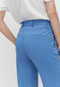 Blå skräddarsydda byxor i en mjuk tygkvalitet, med en ögla på midjebandet, bakfickor och ett slim fit-design.