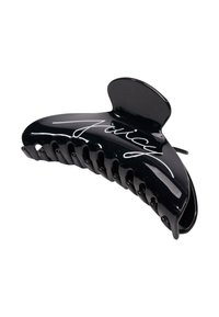 Zwarte plastic haarclip met een gebogen ontwerp en meerdere grip tanden. Voorzien van witte handtekeninglettering aan de voorkant. Glad, glanzend oppervlak.