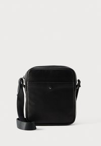 Μαύρο δερμάτινο τσαντάκι χιαστί με ομαλή υφή, ορθογώνιο σχήμα, ρυθμιζόμενο λουρί και μπροστινή τσέπη με φερμουάρ. Διαθέτει μινιμαλιστικό σχεδιασμό.