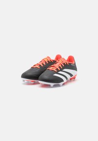 Scarpette da calcio nere con strisce bianche, lacci arancioni e una parte superiore testurizzata. Caratterizzano un design a profilo basso e tacchetti stampati sulla suola.
