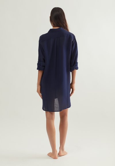 Tengerészkék, vászon ingetípusú ruha laza szabással, felgöngyölt ujjakkal, hátul yoke részlettel és térd alá érő szegéllyel. Sima tapintású, könnyű anyagból készült.