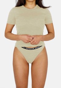 Helles beige T-Shirt mit kurzen Ärmeln aus weichem Material, kombiniert mit einem hellen beigen Tanga mit einem schwarzen Logo-Bund.