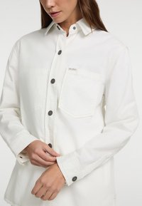 Witte, lange mouwen blouse van zachte stof, met een button-down kraag, drukknoopsluiting en een borstzak met een label.