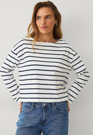 Witte lange mouwen top met marineblauwe horizontale strepen, voorzien van een bootnek en een relaxte pasvorm, gecombineerd met blauwe denim jeans.
