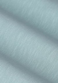 Gros plan d'un tissu bleu clair avec des plis lisses et une fine texture tissée diagonale.