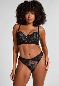 Schwarzes Spitzen-BH- und String-Set mit Blumenmustern, gezackten Kanten und verstellbaren Trägern. Halbtransparentes Material mit schwarzen Akzenten.