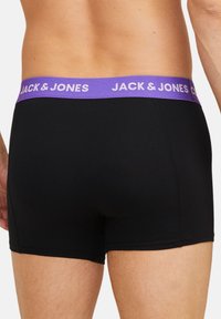 Mustat boxerit, joissa on violetti joustava vyötärö, johon on kirjailtu teksti "JACK & JONES." Sileä kangas ja vartalonmyötäinen muotoilu.