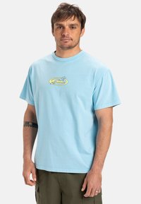 Light blue cotton t-shirt with a round neckline, short sleeves, and a yellow graphic design featuring mountains and stars on the chest.