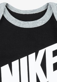 Svart bomull T-skjorte med grå ribbet rund hals og en iøynefallende hvit merkevarelogo på forsiden. Myk tekstur og moderne design.