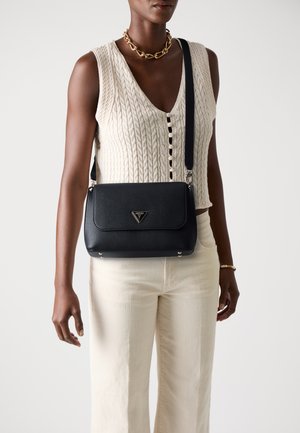 Borsa a tracolla in pelle nera con un design strutturato, hardware in acciaio inox e dettagli con logo. Indossata a tracolla con una cintura regolabile. Finitura testurizzata.
