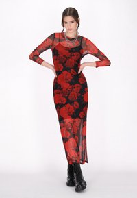 Langes, figurbetontes Kleid aus transparentem schwarzem Stoff mit einem roten Rosenmuster. Verfügt über lange Ärmel und einen hohen Schlitz, kombiniert mit schwarzen Schnürstiefeln.