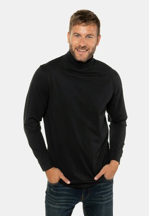 Schwarzes Rollkragenshirt aus weichem Stoff, mit langen Ärmeln und einer taillierten Passform, kombiniert mit blauen Jeans.