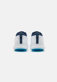 White athletic shoes with navy accents, a textured upper, and blue rubber spikes on the outsole. A looped heel tab for easy wear.