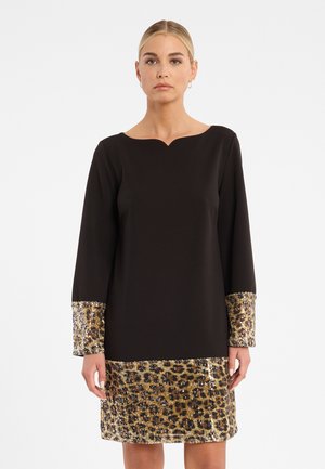 Zwarte jurk met een gegolfde halslijn en lange mouwen, voorzien van schitterende gouden luipaardprint-accenten bij de manchetten en de zoom.