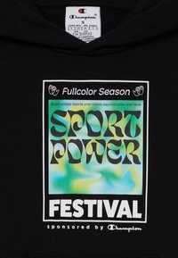 Hoodie noir avec une impression graphique portant "SPORT POWER FESTIVAL" en lettres grasses, sur un fond dégradé coloré.