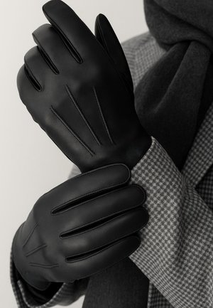 Black leather gloves with five fingers and stitch detailing. Texture appears smooth, positioned over a gray patterned scarf.