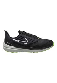 Zapatilla de running negra con un upper texturizado, acentos reflectantes blancos, entresuela gris acolchada y suela de goma verde para tracción.