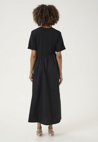 Juodas maksi suknelė trumpomis rankovėmis, su susirinkusia juosmens linija ir laisvu sijonu. Minkšta medžiaga su sklandžiu paviršiumi.