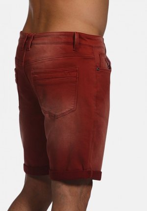 Shorts en denim rouge avec un ourlet roulé, dotés de poches arrière et de détails de couture subtils. Texture lisse avec un design ajusté.