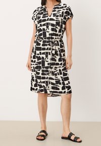 Černobílé šaty se vzorem, výstřihem do V, krátkými rukávy a stahováním v pase, vyrobené z lehké látky, s volným střihem.