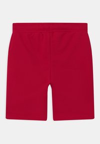 Czerwone bawełniane spodenki z elastycznym pasem, o gładkiej teksturze i długości do kolan. Bez widocznych wzorów ani elementów metalowych.