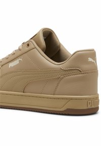 Sneaker Puma marrone con pelle testurizzata, striscia laterale cucita, suola in gomma e logo Puma visibile sul lato e sul tallone.