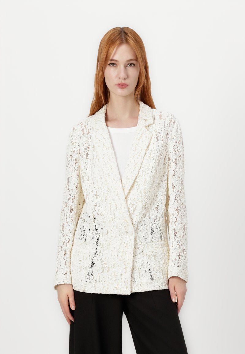 White lace blazer with a textured pattern, tailored design, notched lapels, and two front pockets, paired with a simple white top.
