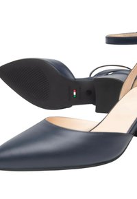 Scarpe in pelle blu navy a punta, con finitura liscia, una sottile cinghia alla caviglia e un piccolo tacco a blocco. Logo del marchio visibile sulla suola.
