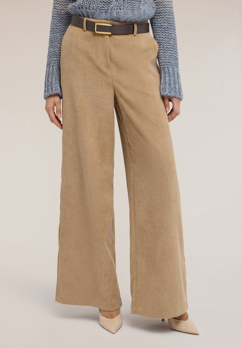 Spodnie szerokie z sztruksu w kolorze beżowym z pionowymi prążkami, zestawione z ciemnobrązowym paskiem z prostokątną złotą klamrą.
