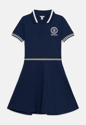 Tmavomodré polo šaty s krátkymi rukávmi, golierom a manžetami s bielymi pruhmi, zapínaním na gombíky vpredu, rozšírenou sukňou a logom Guess na hrudi.