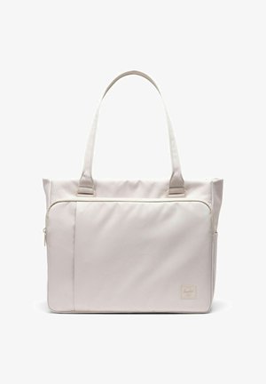 Sac fourre-tout beige clair avec deux poignées, une grande poche avant zippée, et une petite étiquette de marque en bas à droite.