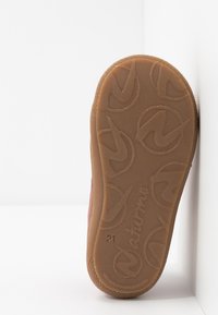 Semelle en caoutchouc de couleur marron avec un motif texturé. Construction robuste avec une légère courbure au niveau des orteils et un bord lisse.