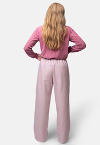 Lichtroze langemouwen top gecombineerd met wijde verticale gestreepte broek in lichtroze en wit, met een elastische tailleband.