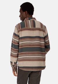 Camicia a maniche lunghe con motivo a strisce in beige, verde e bordeaux. Presenta un colletto, polsini abbottonati e una vestibilità rilassata.