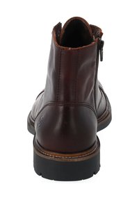 Bottine en cuir marron avec des coutures, fermeture éclair sur le côté et semelle en caoutchouc. L'intérieur présente une doublure douce et un design à bout rond.