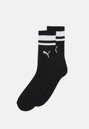 Calcetines de tripulación negros con franjas horizontales blancas en el puño y un pequeño logo blanco. Fabricados con un tejido acanalado de suave textura.