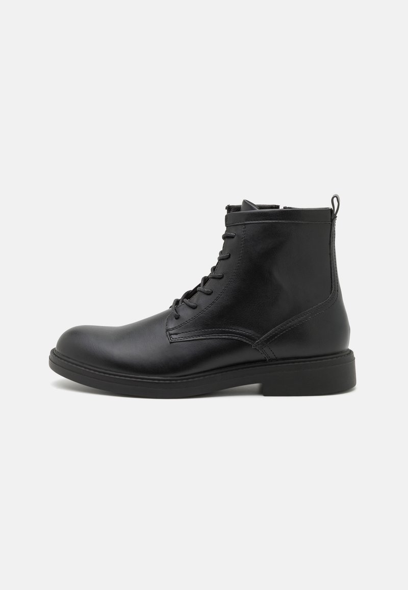 Bottine noire en cuir à lacets avec languette, bout rond et semelle plate, présentée de profil sur fond blanc.