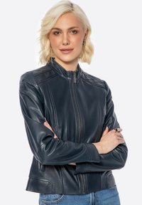 Giubotto in pelle blu navy con chiusura a zip, colletto alto e superficie liscia. Presenta cuciture alle spalle e tasche laterali, con una silhouette aderente.