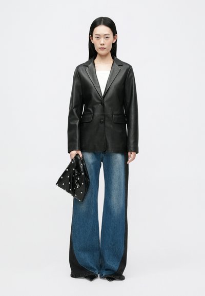 Blazer de couro preto com colarinho de lapela e fecho de botão único, combinado com jeans de perna larga com um lavagem degradê e painéis laterais pretos.