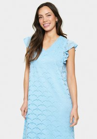 Rochie dantelată de culoare albastră deschisă, cu decolteu în V, mâneci volănuțe și un model cu margini ondulate pe întreaga țesătură. Textură fină și croială lejeră.