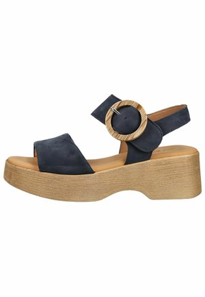 Sandale à plateforme bleu marine avec larges brides, grosse boucle ronde en bois, bout ouvert et semelle texturée beige avec talon compensé.