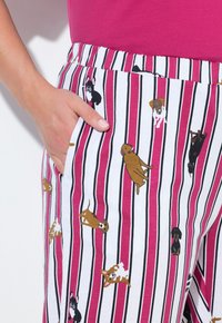 Bawełniane spodnie do piżamy w wielokolorowy paskowany wzór, z małymi ilustracjami psów w kolorach brązowym, czarnym i białym. Posiadają boczną kieszeń.