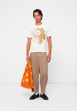 Hvit T-skjorte med et gradientbrunt blomsterdesign, beige vide bukser og en oransje blomster toteveske. Svarte sko og hvite sokker.