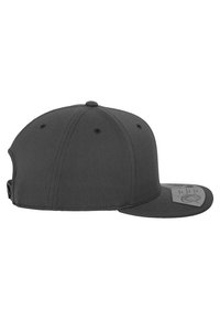 Sort fitted caps med en let buet skygge, tekstureret stof og et rektangulært mærke på forsiden med plejeinstruktioner.