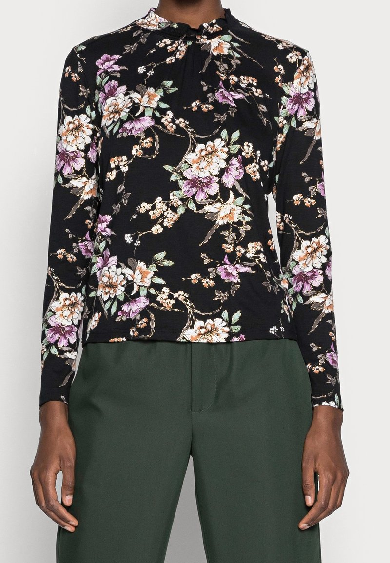 Maglietta nera a maniche lunghe con un motivo floreale in viola, bianco e verde. Design a collo alto con dettagli arricciati al colletto.