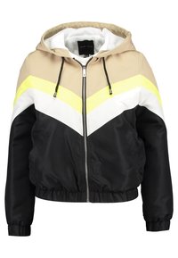 Chaqueta bomber con capucha en materiales mixtos, con un patrón de chevrón en tonos beige, negro, blanco y amarillo neón. Puños y dobladillo elásticos con cierre de cremallera.