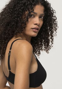 Mustat braletit säädettävillä olkaimilla, pehmeä tekstuuri ja kolmion muotoiset kupit. Sisältää sileän muotoilun ja vähäistä varustusta tukemiseen.