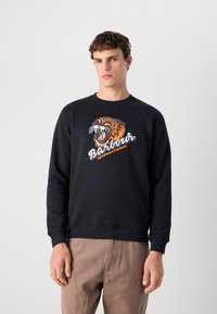 Fekete pamut pulóver, amelyen egy ordító tigris grafika szerepel narancssárga és fehér színben, alatta a "Barbour International" felirattal.